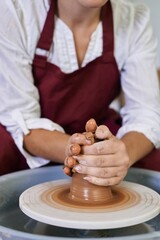 closeup female hands twist clay on a potter's wheel
