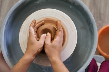 close-up female hands twist ceramic utensils on a potter's wheel top view