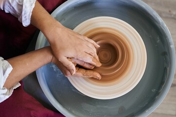 close-up female hands twist ceramic utensils on a potter's wheel top view