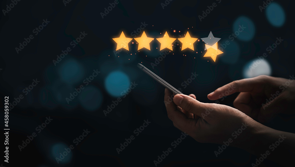 Poster Hand holding and using smartphone with virtual five golden stars with glowing light for the best customer client evaluation score after use product and service concept.