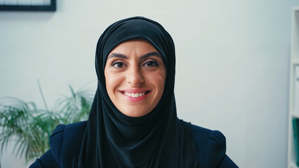 cheerful arabian businesswoman in hijab looking at camera