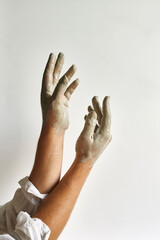 beautiful female hands on a light background smeared in gray clay