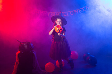 Fototapeta na wymiar Funny child girl in witch costume for Halloween with pumpkin Jack.