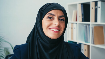 positive arabian businesswoman in hijab looking at camera
