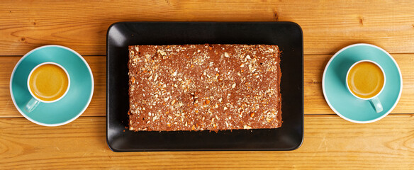 Homemade chocolate cake and two cups of coffee espresso on wooden table. Top view.