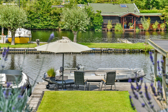 Motorboats on river between lawns with parasol in suburb