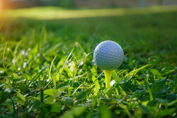 Golf ball on tee in beautiful golf course at sunset background.