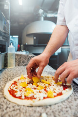 Chef puts cheese on pizza. Catering kitchen work.