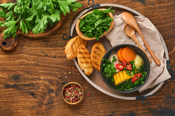 Chilean meat soup with pampkin, corn, fresh coriander and potatoes on old wooden table background. Cazuela. Latinamerican food.