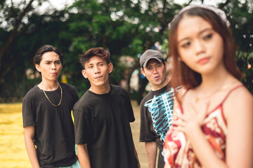 Three rude men catcalling and making provocative gestures to a nervous lady while trailing her from behind. Street harassment concept.