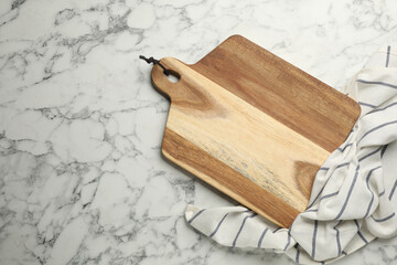 Wooden cutting board and kitchen towel on white marble table, flat lay with space for text. Cooking...
