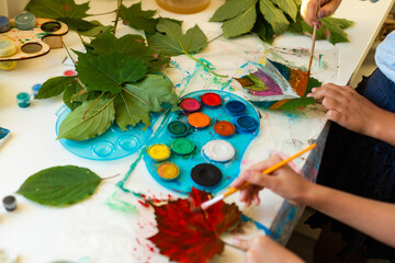 two schoolgirls paint the leaves