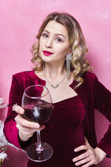 woman in burgundy dress stretches out her hand with a glass of wine