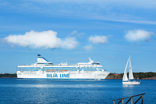 Silja line ferry boat and sailing yacht nearby in blue sea under a clear sky - Finland, Helsinki, August 2018