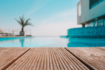 Empty wooden deck with swimming pool , Beautiful minimalist pool side view with clear blue sky . Vintage filter color apply - obrazy, fototapety, plakaty