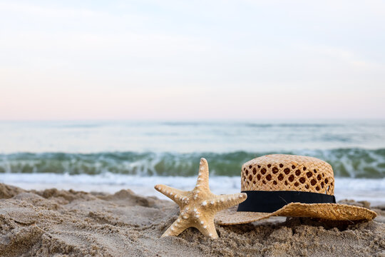Straw hat and starfish on beautiful sand by the sea
