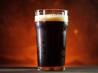 A glass of dark beer in the center, orange backlight.