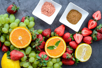Various fruits and berries on dark stone table, vegan food in the kitchen