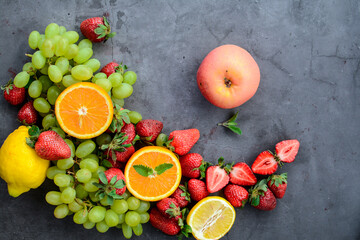 Various fruits and berries on dark stone table, vegan food in the kitchen
