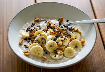 Healthy oatmeal porridge with banana, walnuts and cacao nibs.