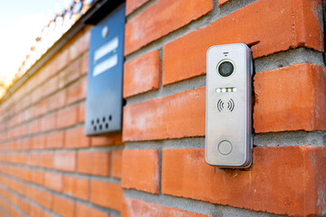 Video intercom outdoors. Call with a video camera on a red brick fence.