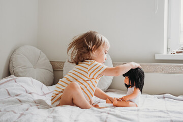 Toddler girl playing with her doll at home