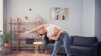 Obraz premium Slim sportswoman bending during home work out