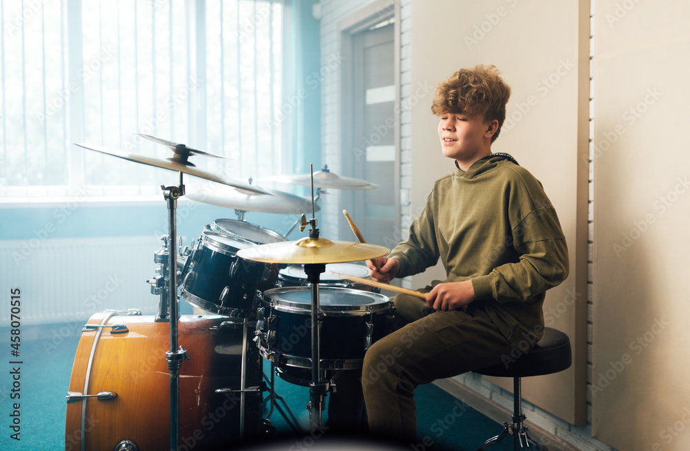 Wall mural a boy enjoys music playing the drum set