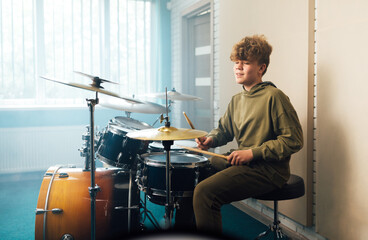 A boy enjoys music playing the drum set