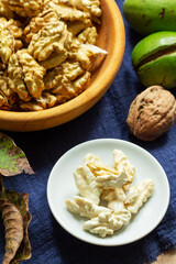 Young walnuts, shelled and in shell, walnut leaves. Rustic style.