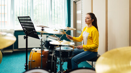 Fototapeta na wymiar A girl in a music school learns how to play the drums from the notes. Lesson at the music school.