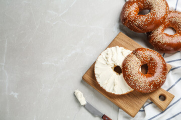 Delicious bagel with cream cheese on light table, flat lay. Space for text - obrazy, fototapety, plakaty