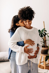 Romantic young woman embracing her pregnant wife at home