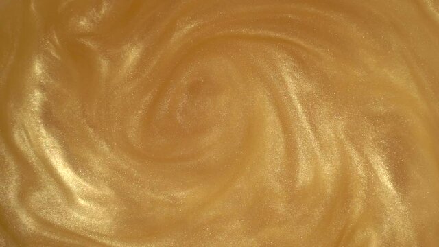 Gold glitter abstract background. Shiny liquid gold paint flows slowly onto the surface. Holidays, new year, fashion, abstract art concept video