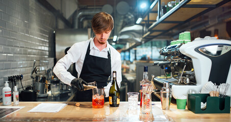 Barman pours the ingredients into a glass for mixing. Cocktail preparation process.