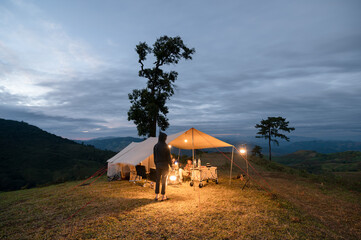 Camping with young asian friends in large tent on hill in campsite