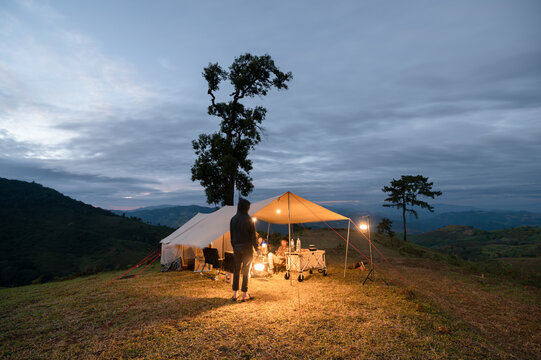 Camping with young asian friends in large tent on hill in campsite - Powered by Adobe
