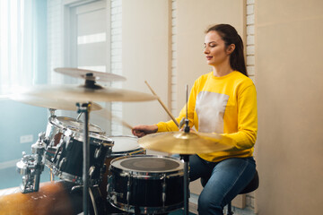  Woman practicing drumming on drum set - obrazy, fototapety, plakaty
