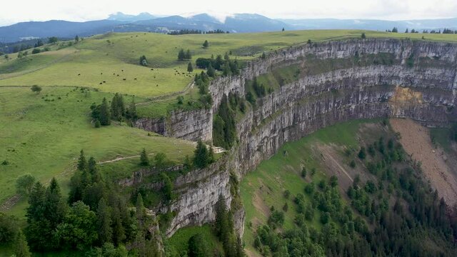 Descending drone shot of Creux du Van in Switzerland, located at the border of the cantons of Neuenburg and Vaud