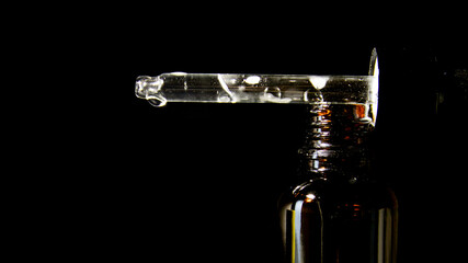 Dropper bottle for cosmetic product isolated on black background. Package design. Creative presentation, front view with copy space. Mockup of a cosmetic product.