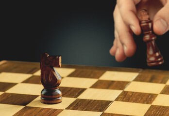 Human hand of businessman wearing suit moving chess figure in competition success play.