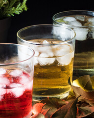 Three glasses filled with red, yellow and green liquids  and ices