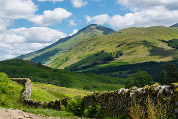 Obraz premium Along the West highland Way in Scotland. An old stone wall runs along the hiking path in the Glen Falloch valley