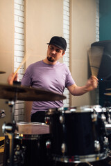 The guy plays the drum kit vigorously. Playing musical instruments.