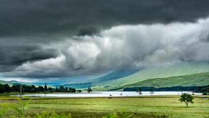 Landscape along the West highland Way in Scotland. Large black clouds laden with rain roll over Loch Tulla. - 458076531