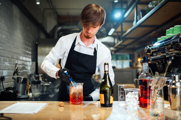 Barman pours the drinks ingredients into a mixing bowl using a liquor dispenser. Cocktail preparation process