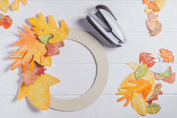 Step-by-step tutorial autumn paper wreath. Step 4: use stapler to fix leaves in circle on cardboard...