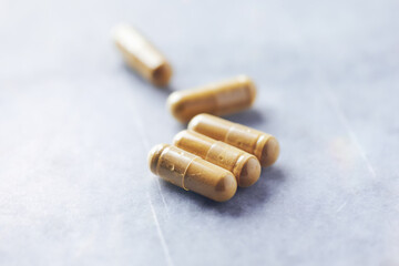 Turmeric capsules. Bright stone background. Close up. Copy space. 