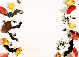 Top view white background with bats, spiders and autumn leaves with copy space for text. Mock up of Halloween holiday concept.