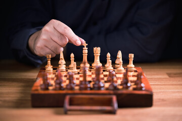 Man going to start playing chess on the table, small wooden chess collection, strategy or planning concept
